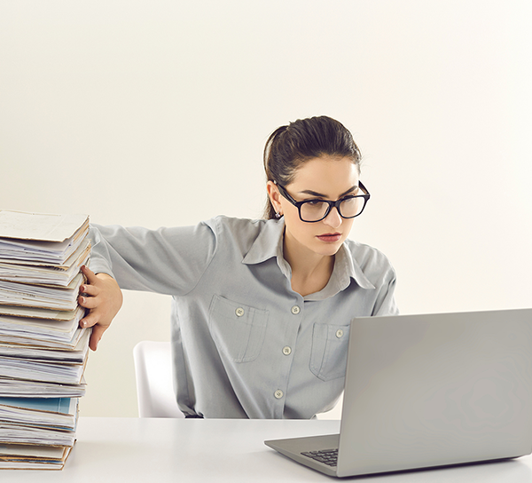Woman pushes files aside and looks into her laptop