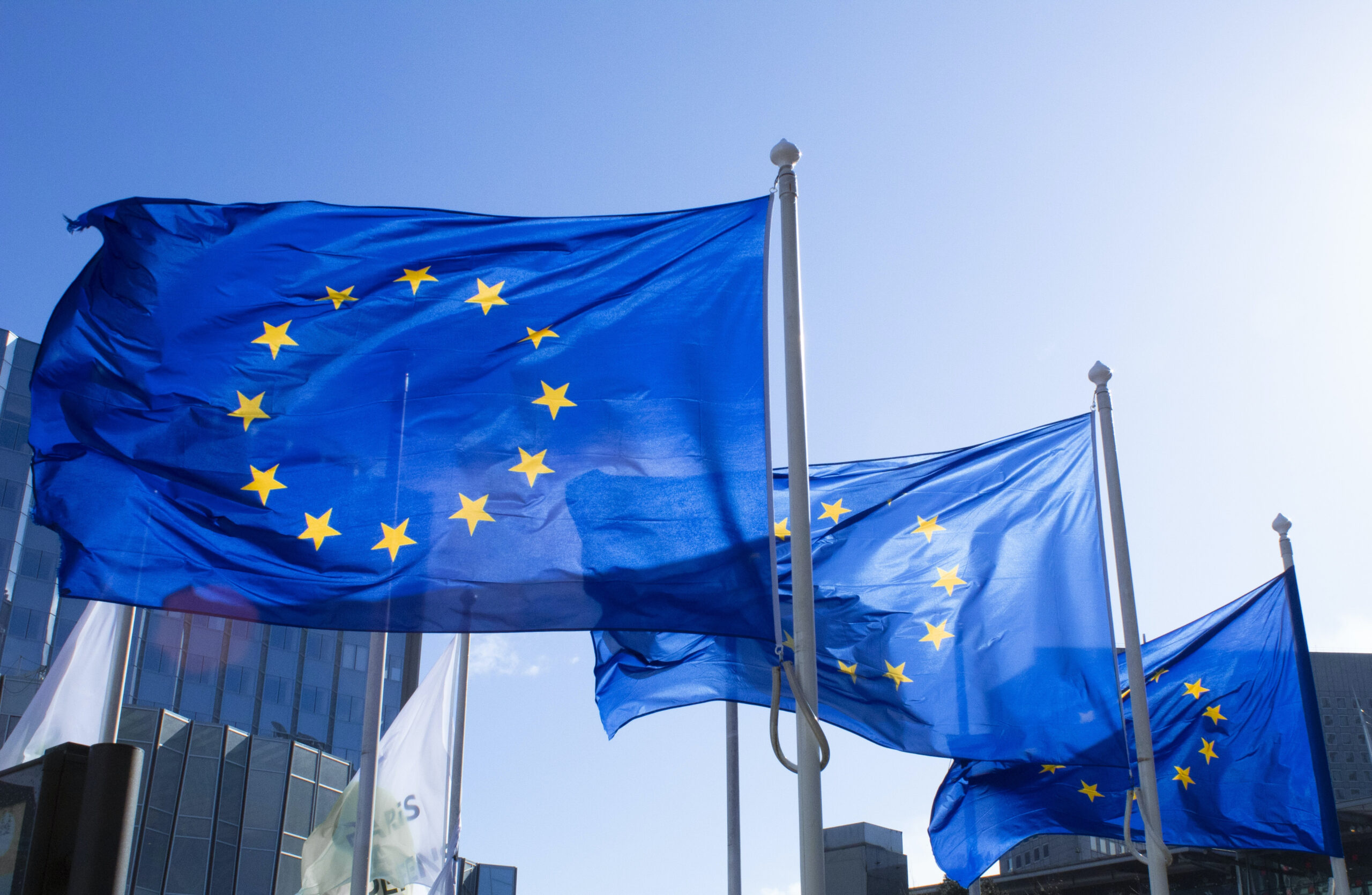 European flags waving in the wind against a blue sky.