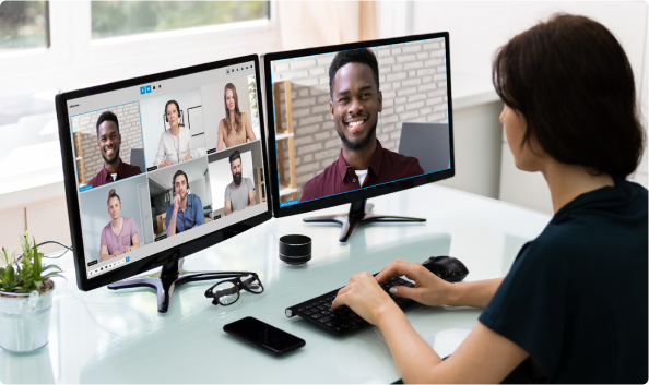 Woman at her desk with two screens. On one screen you can see the speaker in full screen.